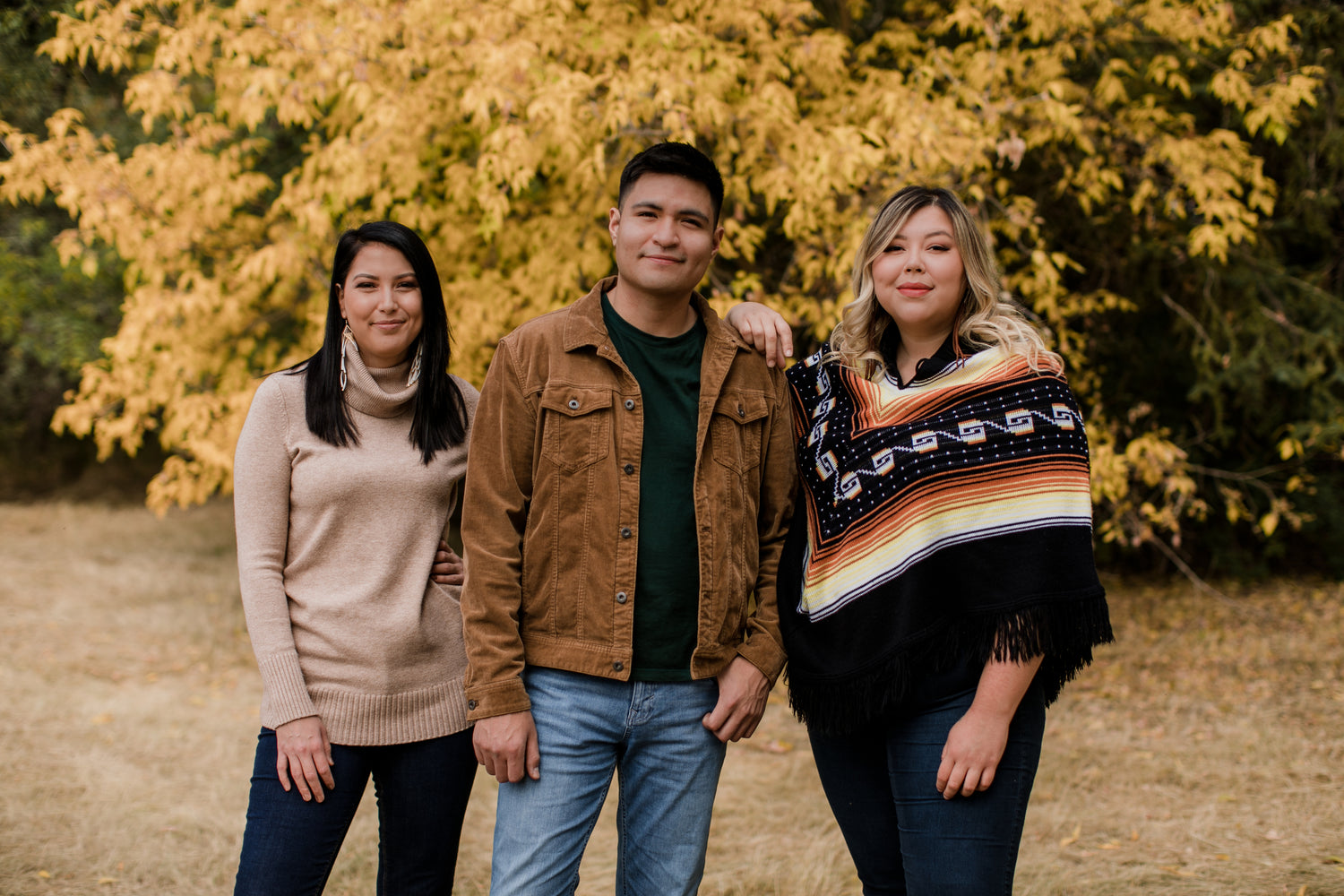 Three Indigenous people stand together in nature